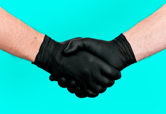 握手两个手乳胶黑色的手套握手之间的两个人医生和病人个人安全和卫生薄荷颜色背景特写镜头帮助概念帮助手