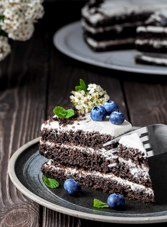 片自制的鸟樱桃蛋糕与酸奶油装饰与蓝莓和薄荷叶子板的叉需要片蛋糕西伯利亚传统的春天蛋糕黑暗木背景