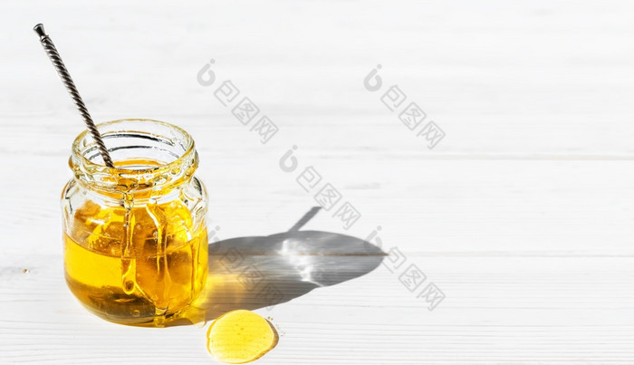 有机自然蜂蜜玻璃Jar白色木背景特写镜头古董勺子开放Jar与蜂蜜明亮的阳光照通过Jar蜂蜜