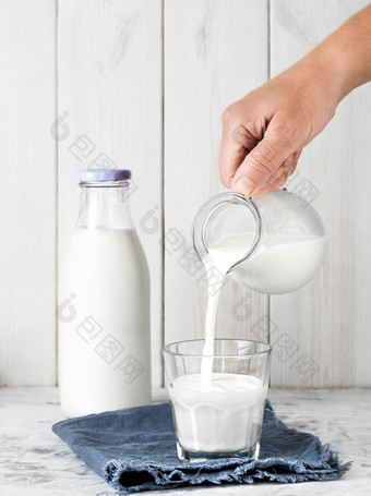 <strong>牛奶</strong>倒成玻璃从壶瓶<strong>牛奶</strong>白色木背景特写镜头早餐概念健康的食物可重用的玻璃器皿<strong>牛奶</strong>倒成玻璃从壶