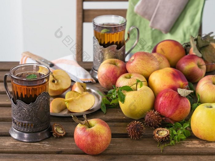 新鲜的红色的苹果和切片苹果木表格野生葡萄叶子和薄荷叶子两个眼镜薄荷茶秋天收获的水果的野生栗仍然生活