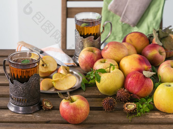新鲜的红色的苹果和切片苹果木表格野生葡萄叶子和薄荷叶子两个眼镜薄荷茶秋天收获的水果的野生栗仍然生活