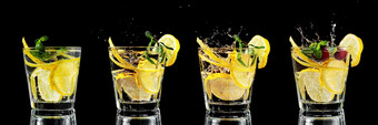 四个玻璃与柠檬水莫吉托鸡尾酒与柠檬和薄荷冷饮料黑色的背景溅冰下降成眼镜复制空间关闭