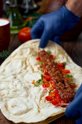 的过程使阿达纳烤肉串情况烤肉串的老板传统的土耳其阿拉伯语东方烤肉串卷与沙拉和香料木背景特写镜头与浅深度场
