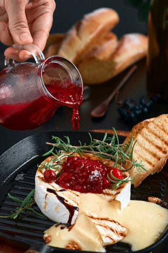 质奶酪铸铁锅烤箱烤与无花果核桃和迷迭香特写镜头黑色的背景撒上奶酪与蔓越莓酱汁魔杖葡萄和蔓越莓酱汁背景