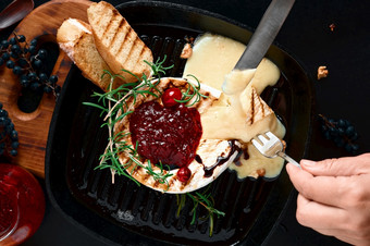 质奶酪长柄平底煎锅与核桃和迷迭香蔓越莓酱汁与奶酪前视图黑色的背景片魔杖煎锅女孩手与餐具在菜