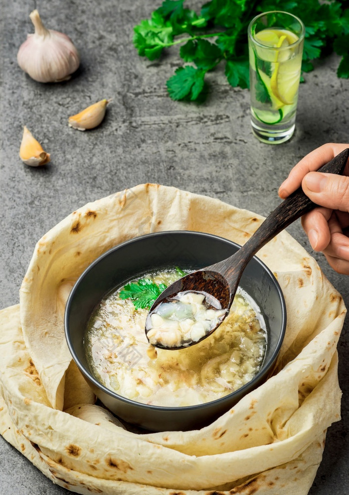 肉汤与卡什肉手与勺子在的汤传统的热菜东部国家受欢迎的亚美尼亚阿塞拜疆伊朗伊拉克乔治亚州保加利亚和火鸡特写镜头