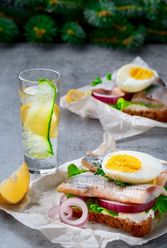 三明治与鲱鱼蔬菜和鸡蛋特写镜头玻璃杜松子酒伏特加的表格零食概念传统的斯莫雷布罗德三明治