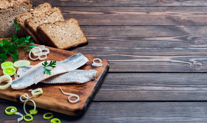 鲱鱼角与欧芹和洋葱切割董事会黑暗木背景与的地方为文本传统的挪威丹麦斯莫雷布罗德成分鲱鱼三明治健康的食物概念