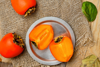 成熟的美味的橙色柿子水果前视图新鲜的柿子半金属板和整个柿子浆果席子席布局木乡村表格