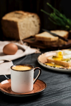 特写镜头杯表示咖啡与不断上升的蒸汽黑色的木表格模糊背景半熟的蛋挖走片面包与黄油奶油和草本植物早餐的想法