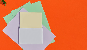 有创意的概念为祝贺的信问候卡模板水平布局与复制空间明信片模型与白色信封和多色的写作纸橙色烧背景