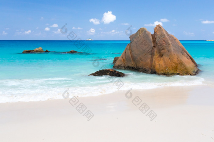 海滩与蓝色的水和蓝色的天空和白色沙子和一些岩石海滩与蓝色的水和蓝色的天空和一些岩石