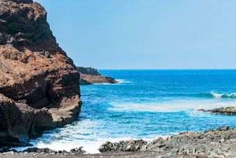 海洋岩石海岸附近的角有一部tenerife沃卡尼克岩石与明亮的和充满活力的蓝色的海波阳光明媚的一天金丝雀岛屿海洋岩石海岸附近的角有一部tenerife沃卡尼克岩石与明亮的和充满活力的蓝色的海波阳光明媚