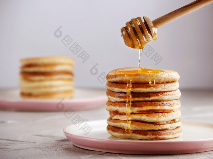 堆栈煎饼与蜂蜜勺子和倒蜂蜜光回来堆栈煎饼与蜂蜜勺子和倒蜂蜜光背景