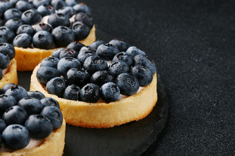 蓝莓蛋挞的表格关闭两个小果馅饼与新鲜的蓝莓蓝莓蛋挞的表格特写镜头两个小果馅饼与新鲜的蓝莓