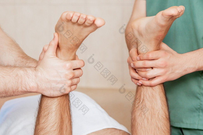 男人。接收腿按摩他的脚两个按摩治疗师关闭男人。接收腿按摩