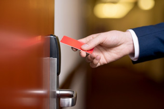 手现代商人持有红色的塑料卡关闭木通过酒店房间得到内部手现代商人持有红色的塑料卡关闭木通过