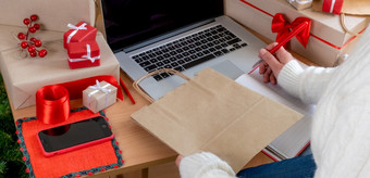 交付rsquo手使用移动PC附近包装袋和礼物rsquo盒子在线购物和交付概念礼物手交付移动PC工人红色的购物袋交付在线白色衣服