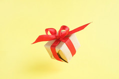 礼物盒子与红色的丝带黄色的背景零重力悬浮milimalism概念销售购物圣诞节假期和生日礼物盒子与红色的丝带黄色的背景零重力悬浮milimalism概念销售购物圣诞节假期和生日