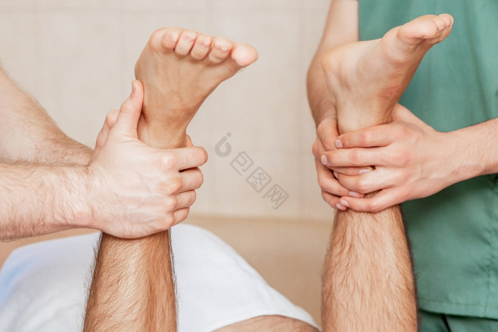 男人接收腿按摩他的脚两个按摩治疗师关闭男