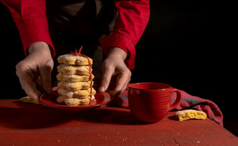 手集饼干<strong>红色</strong>的杯咖啡茶<strong>红色</strong>的木表格的黑色的背景<strong>手持</strong>有<strong>红色</strong>的饼干礼物黑色的背景杯咖啡茶