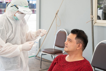 医生佩普西装和亚洲男人。病人检查新冠病毒标本执行鼻咽口咽拭子从鼻和口服医院执行鼻咽口咽拭子