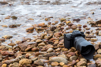 数码<strong>单反相机</strong>相机与长焦<strong>镜头</strong>湿从水海波石头海滩当旅行和测试使用的极端的环境演示防水摄影师数码<strong>单反相机</strong>相机石头海滩湿从水海波