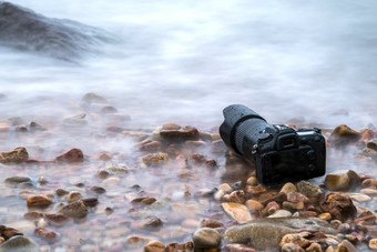 数码单反相机相机与长焦镜头湿从水海波<strong>石头</strong>海滩当旅行和测试使用的极端的环境演示防水<strong>摄影</strong>师数码单反相机相机<strong>石头</strong>海滩湿从水海波