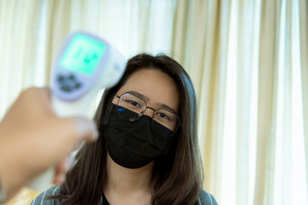 亚洲女人穿面具呼吸保护面具对疫情流感科维德电晕病毒和身体<strong>温度</strong>健康检查<strong>测量</strong>发热水平数字红外<strong>温度</strong>计为医疗保健女人穿面具保护流感与thermoscan