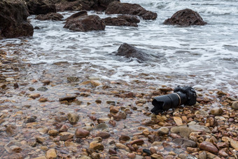 数码单反相机相机与长焦镜头湿从水海波<strong>石头</strong>海滩当旅行和测试使用的极端的环境演示防水<strong>摄影</strong>师数码单反相机相机<strong>石头</strong>海滩湿从水海波