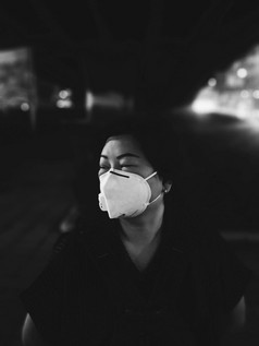 亚洲女人使用面具呼吸保护面具对空气与烟雾灰尘超过的标准价值曼谷城市与坏天气空气污染路与交通曼谷女人使用面具保护烟雾灰尘城市