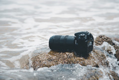 数码单反相机相机与长焦镜头海滩湿从水海波当旅行和测试使用的极端的环境演示防水摄影师数码单反相机相机海滩湿从水海波