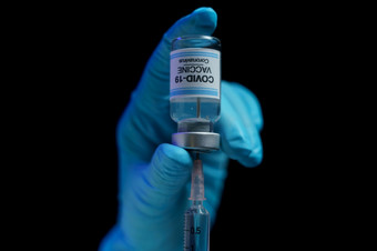 手蓝色的手套持有疫苗和注射器注射为预防免疫接种和治疗从电晕病毒感染