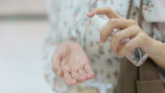 女人使用手洗手液喷雾从她的手袋预防冠状病毒