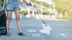 女人使用垃圾收集器设备保持塑料浪费成黑色的袋地面