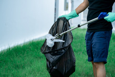 男人。手使用垃圾收集器设备保持塑料浪费成黑色的袋公园