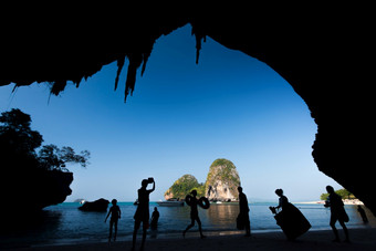 集团游客采取照片和放松的千天哪海滩阳光明媚的夏天视图从内部的洞穴看出旅游景点甲米泰国轮廓焦点游客