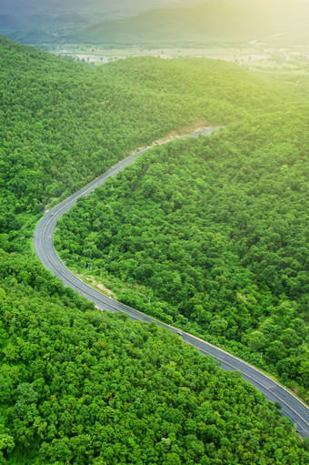 空中视图山路日出曲线沥青路通过山范围和绿色森林