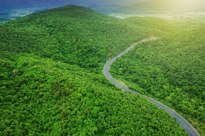 空中视图山路日出曲线沥青路通过山范围和绿色森林