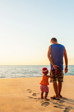 兴奋亚洲小女孩持有她的父亲而走的日落海滩为的第一个时间