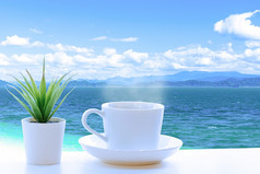 白色陶瓷杯咖啡海视图阳台蓝色的海热带岛屿白色云的蓝色的天空模糊的背景假期假期