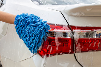 女人手与蓝色的超细纤维织物洗尾灯现代车清洁汽车车洗概念
