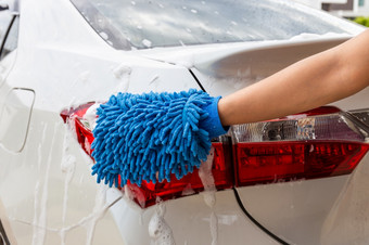 女人手与蓝色的超细纤维织物洗<strong>尾灯</strong>现代车清洁汽车车洗概念