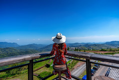年轻的女人坐着的甲板和看自然景观泰国