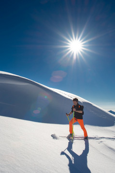 男人。高山滑雪爬滑雪板和海豹皮新鲜的雪强大的阳光明媚的一天