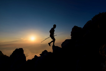 日落轮廓天空奔跑者男人。攀爬高山脊与波兰人
