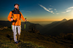 徒步旅行者男人。实践北欧走日落的山