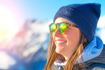 女滑雪与滑雪板微笑和穿滑雪眼镜与反射全景山