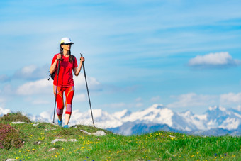 女人穿着旅游红色的与高山与雪走绿色草的前景